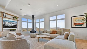 Ein großzügiges Wohnzimmer mit Kamin, großen Fenstern und Blick auf die Landschaft.