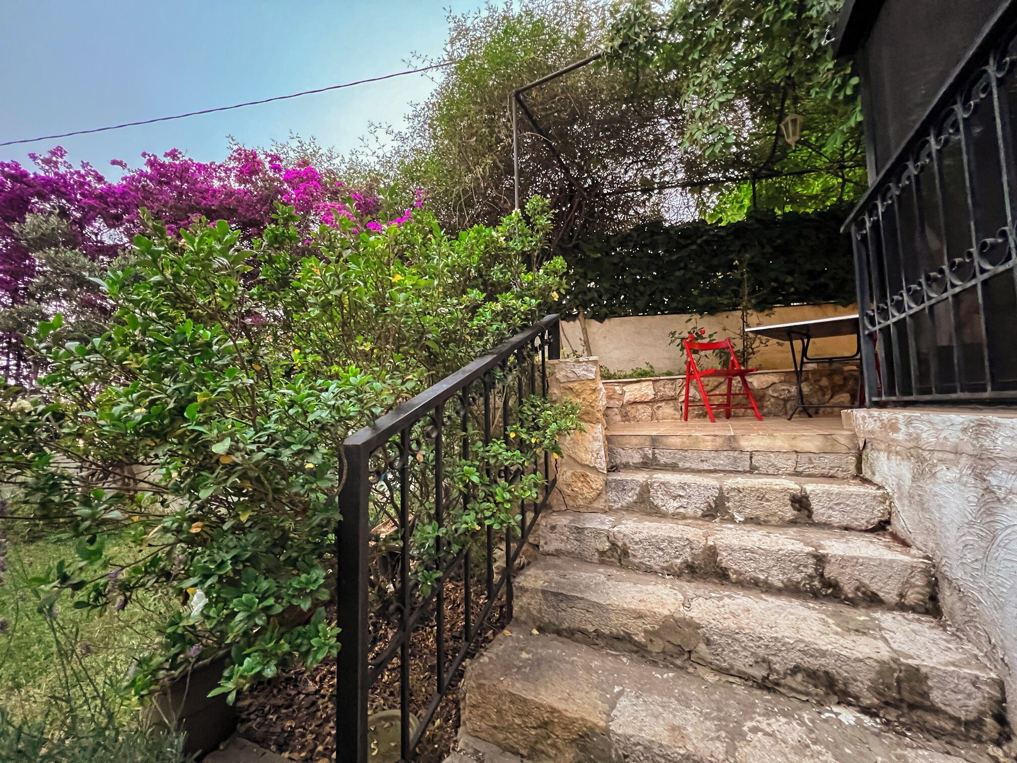 A stone staircase with a metal railing leading to a covered outdoor area.