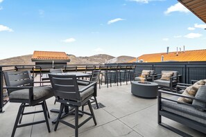 Eine Terrass mit Feuerstelle, Sitzgelegenheit und Blick auf entfernte Gebäude.