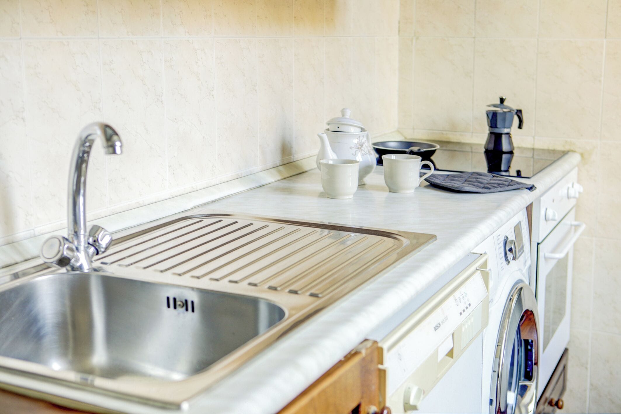 Una cucina con lavello in acciaio inossidabile, macchina da caffè, bollitore ed un tostapane.