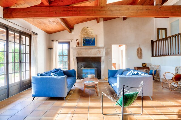 A spacious living room with a fireplace, blue sofas, and a large window.