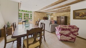 A dining area with a wooden table and chairs, a sofa, and a patterned armchair. - Salignac-Eyvigues, house for 7 with pool (Salignac-Eyvigues)