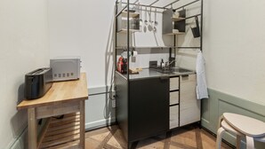 Et lille tekøkken med en toaster, en håndvask og et træbord.