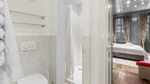Un bagno con il water, doccia e vasca, e una camera da letto con letto e finestra.