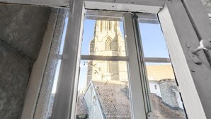 A window with a view of a church tower and adjacent buildings. - Charming studio in Fribourg's old town (Fribourg)