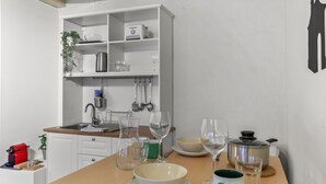 A kitchen with white cabinets, a wooden countertop, a sink, and various kitchen items like a kettle, wine glasses, and a pot. - Charming studio in Fribourg's old town (Fribourg)