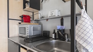 A compact kitchenette with a microwave, toaster, and sink. - Bright studio in Freiburg's old town (Fribourg)