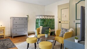 A living room with a sofa set, a coffee table, a dresser, and a fireplace. - Bright studio in Freiburg's old town (Fribourg)