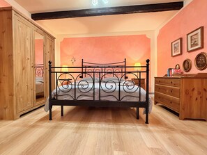 Un dormitorio con cama, armario de madera y cómoda.