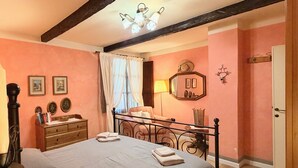 Una camera da letto con un letto, comodini, una cassettiera, uno specchio e una porta.