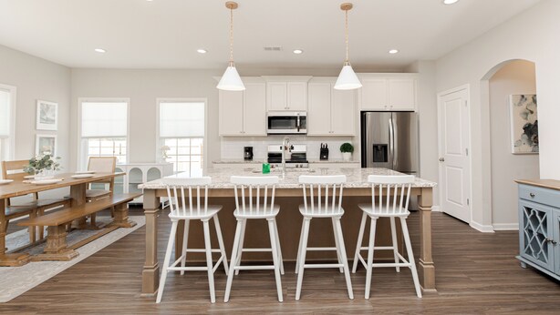 Une cuisine moderne avec des meubles blancs, un grand îlot central doté de tabourets et des appareils électroménagers en acier inoxydable.