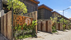 A modern residential building with a brick facade, stone pillars, and a paved walkway.