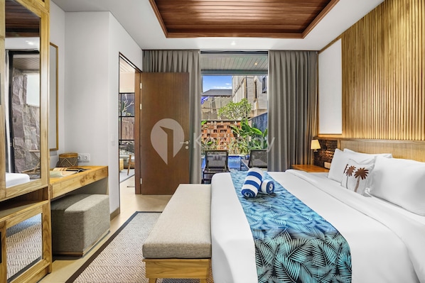 A modern hotel room with a large bed, a wooden headboard, a small desk, and a view of the courtyard.