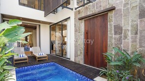 A modern house with a swimming pool, two lounge chairs, and a wooden door.
