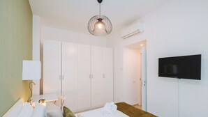 A hotel room with a bed, a TV, a wardrobe, and a lamp.