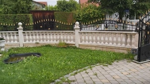 Un área vallada con balaustrada blanca, un camino pavimentado y un pequeño estanque.