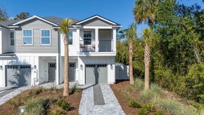 A two-story house with a garage, a covered driveway, and palm trees. - Blue Wave by Team Joseph Ellen (Jacksonville Beach)