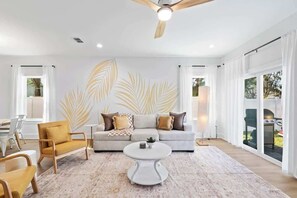 A modern living room with a sofa, armchairs, a coffee table, and a ceiling fan.
