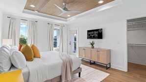 Une chambre à coucher avec un lit, un ventilateur de plafond, une armoire en bois et un panneau accroché au mur.