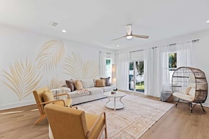 A modern living room with a sofa, chairs, a coffee table, and a hanging chair.