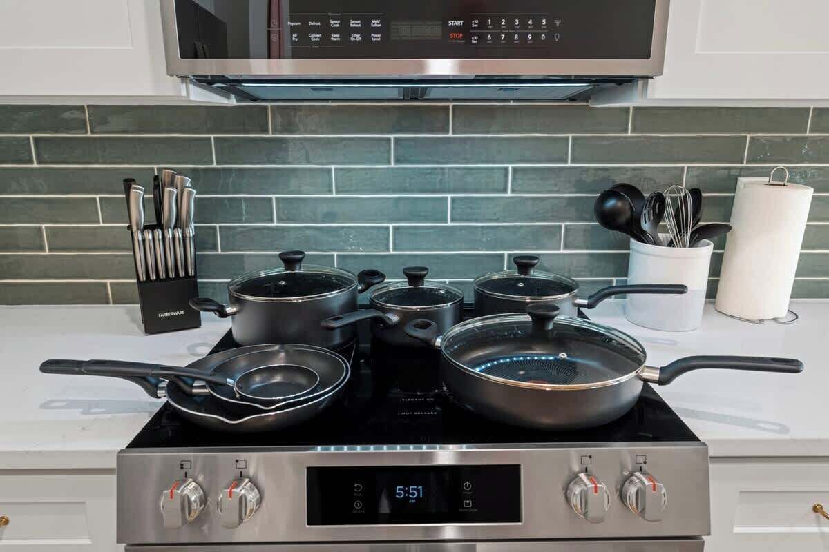 Une cuisine équipée d’une horloge numérique, d’une cuisinière en acier inoxydable et de casseroles.