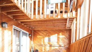 A wooden deck with a bench and a dog, a staircase, and a sign with the letter 'V'. - A Wonderful Vacation Home Set in the Woods with Unique Envelope Architecture (Bessemer)