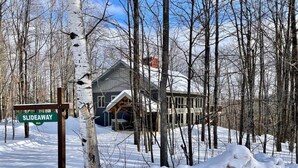 A snow-covered landscape with a wooden signpost indicating 'SLIDEAWAY 404'. - A Wonderful Vacation Home Set in the Woods with Unique Envelope Architecture (Bessemer)