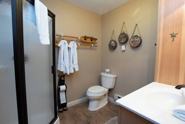 Een badkamer met een toilet, een wastafel en een handdoekhouder met handdoeken. Er zijn decoraties aan de muur en een deur met een ster-vormige handgreep.