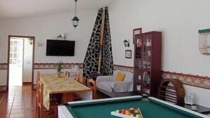A living room with a pool table, a sofa, a dining table, and a television. - Casa Machuca with swimming pool (Tomar)