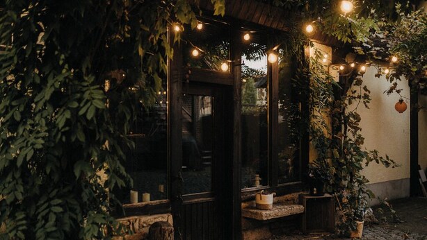 Un'area esterna con sedute, un banco di legno, un tavolo e luci decorative appese.