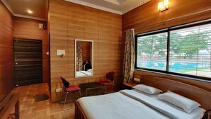 Une chambre d’hôtel avec un mur en bois, un grand lit, un bureau, une chaise et une fenêtre donnant sur l’extérieur.