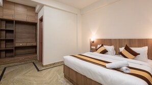 A hotel room with a bed, a wardrobe, and a nightstand with a lamp. - Saavi Hotel Medicity (Gurugram)