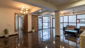 A spacious lobby with a polished marble floor, a reception desk, and seating area with sofas and a coffee table. - Saavi Hotel Medicity (Gurugram)
