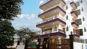 A multi-story building with balconies, a gated entrance, and a clear sky.