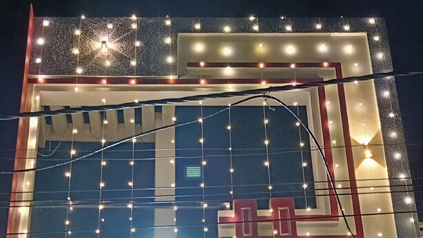 Fachada de edificio con luces de cadena y un letrero en idioma local.