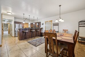 Une cuisine spacieuse avec des meubles en bois, un îlot central doté de tabourets de bar et un éclairage suspendu.