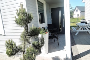 A house with a porch, a small table and chairs, and a potted plant. - Cottage in Niechorze Near Baltic Beach (Rewal)