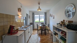 A compact kitchen with a tiled backsplash, a dining area with a table and chairs, and a large wall clock. - Gîte Renardeau: Comfort and Nature in Chassey-Beaupré (Chassey-Beaupré)