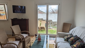 A living room with wicker furniture, a television, and a view of the outside. - Gîte Renardeau: Comfort and Nature in Chassey-Beaupré (Chassey-Beaupré)