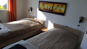 A room with two beds, a painting on the wall, and a window with curtains. - Gîte Renardeau: Comfort and Nature in Chassey-Beaupré (Chassey-Beaupré)
