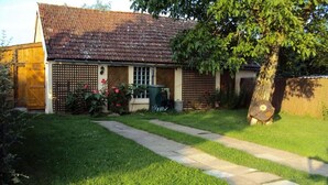 Una casa con techo de tejas, un patio delantero con un sendero y un árbol.