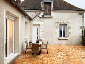 A courtyard with a tiled floor, a table with chairs, and a window.