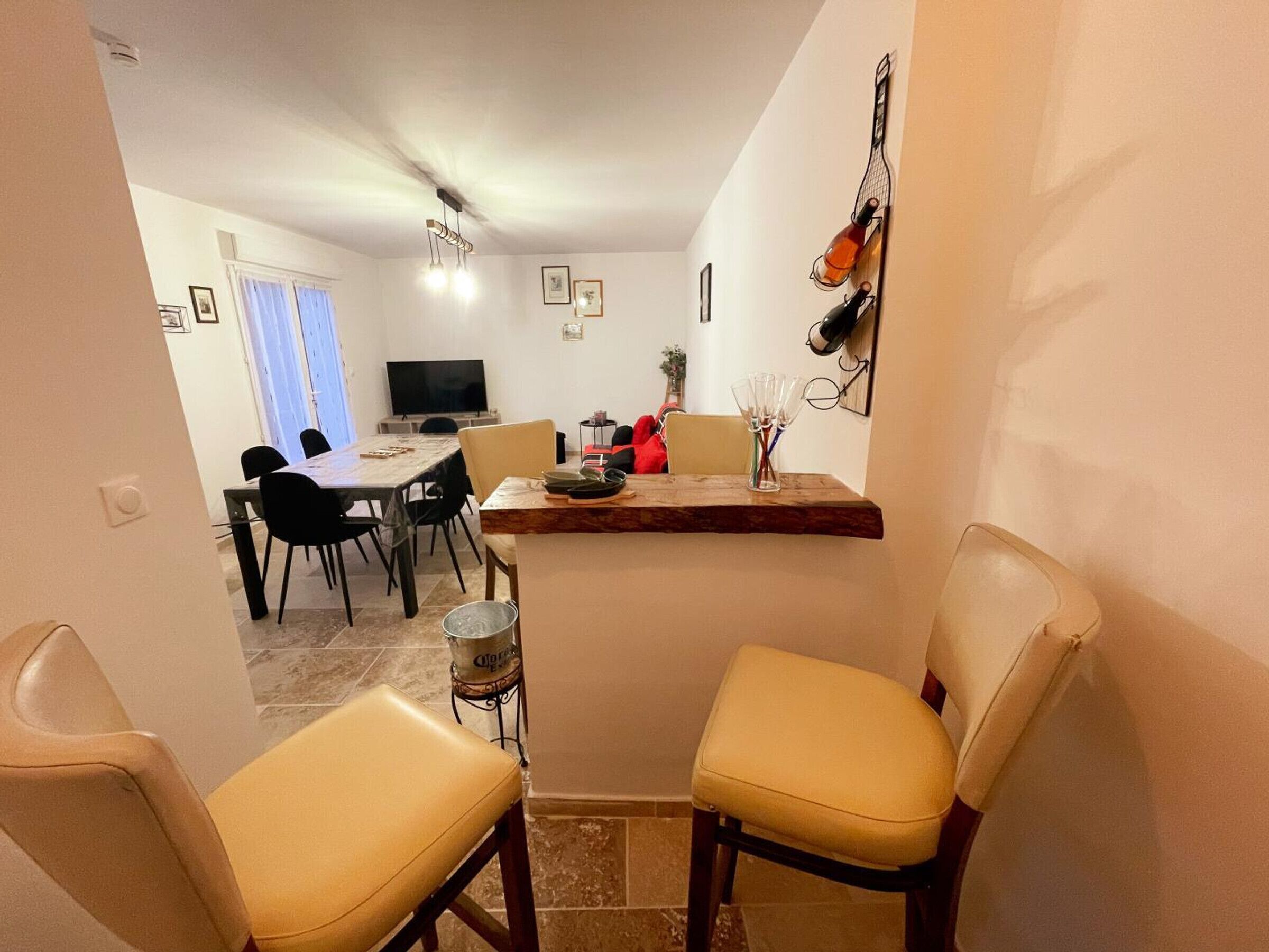 Un coin repas avec une table en bois, quatre chaises et un téléviseur en arrière-plan.