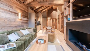 A cozy interior with a wooden ceiling, a fireplace, a green sofa, and a dining area.