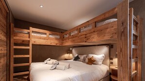 A wooden bunk bed room with a bed, pillows, and a nightstand.