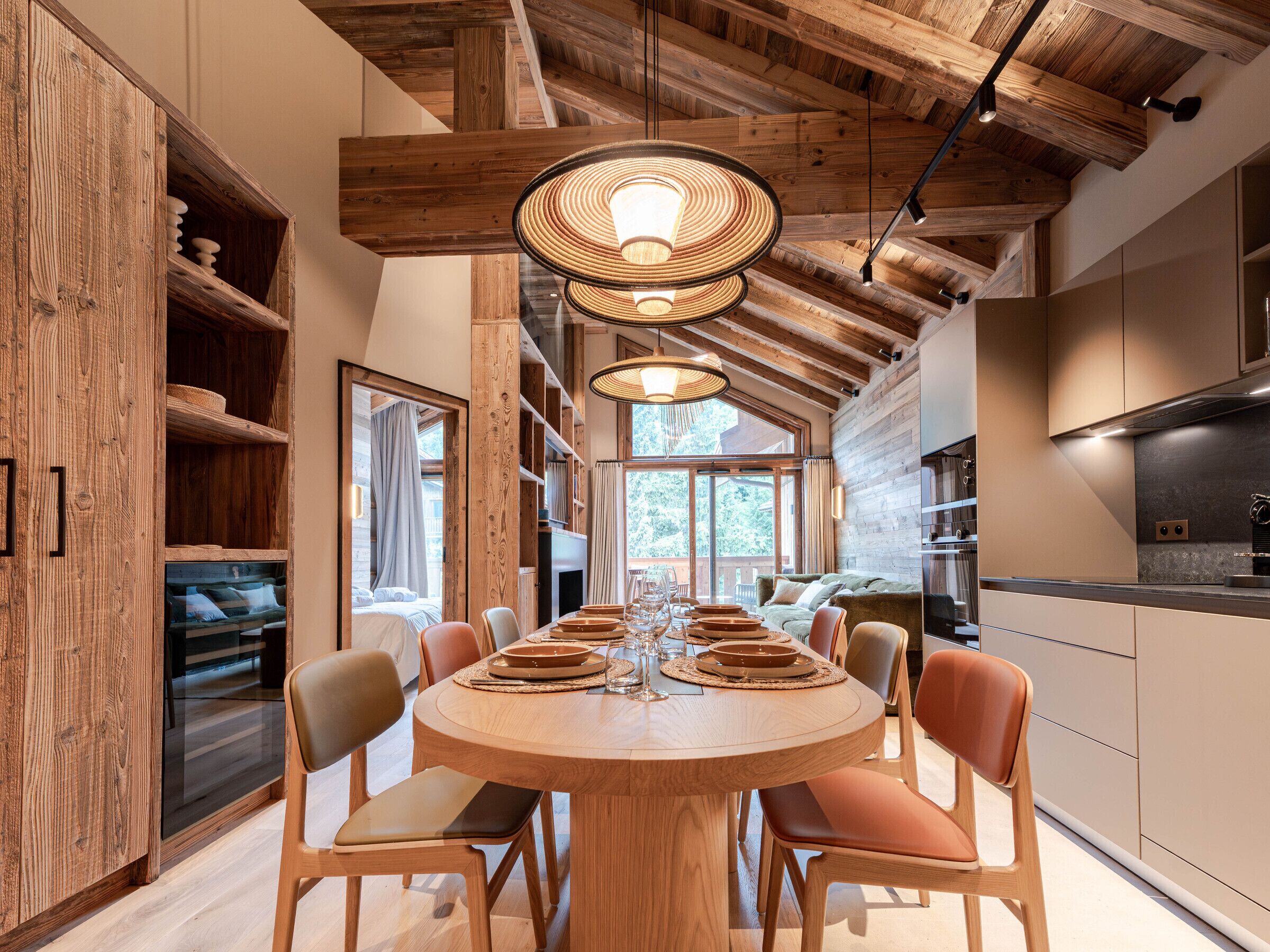 A modern kitchen with wooden beams, a dining area with a round table, and built-in wooden shelving.
