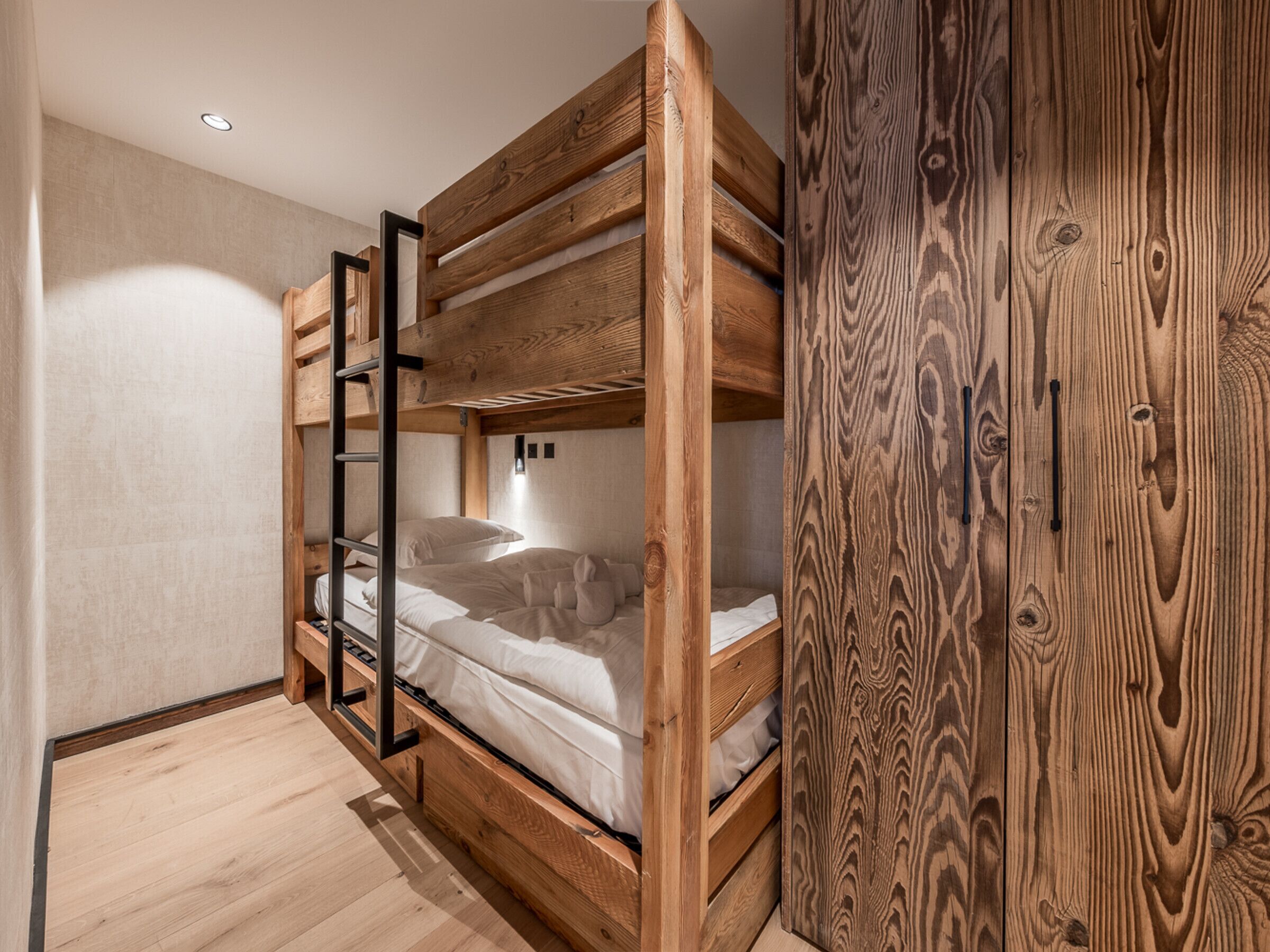 Dormitorio con literas, paredes de madera y armario de madera.