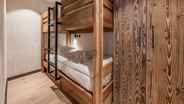 Dormitorio con literas, paredes de madera y armario de madera.