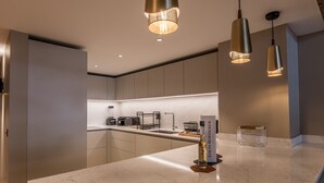 Cozinha moderna com bancada de mármore, iluminação pendente e máquina de café.