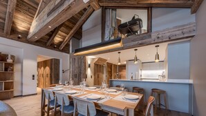 Uma área de jantar moderna com uma mesa de madeira comprida posta para seis pessoas, rodeada por cadeiras.